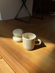 Tasse und Dose auf Holzboden im Sonnenlicht